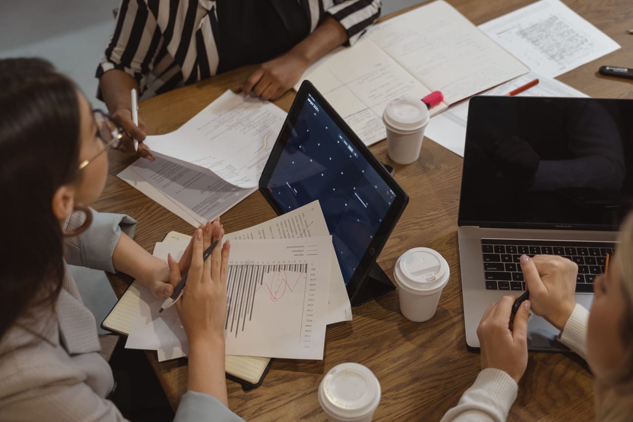 Vista superior de un equipo de trabajo con informes, una tableta y un portátil